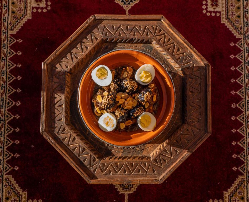 Traditional Moroccan tagine with eggs and almonds served on a carved wooden tray