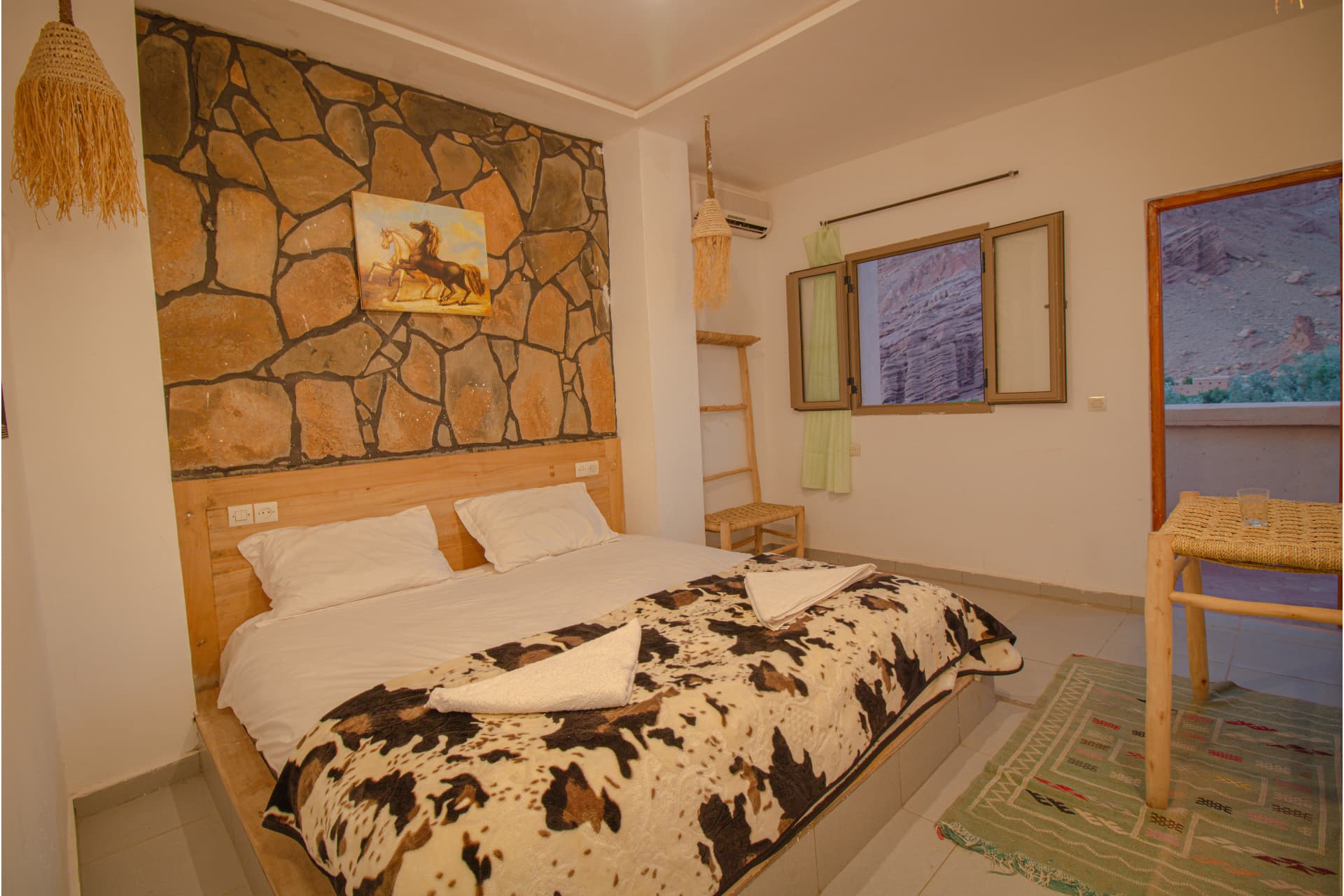 AYOUR — wide bedroom with stone feature wall, double bed and open window onto the canyon