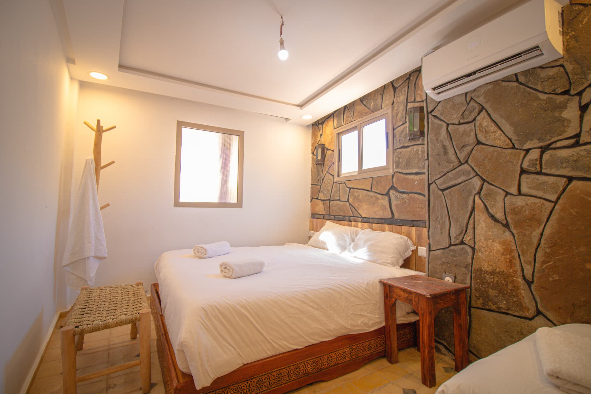 OUARZAZAT — carved wooden bed frame, window light and woven stool