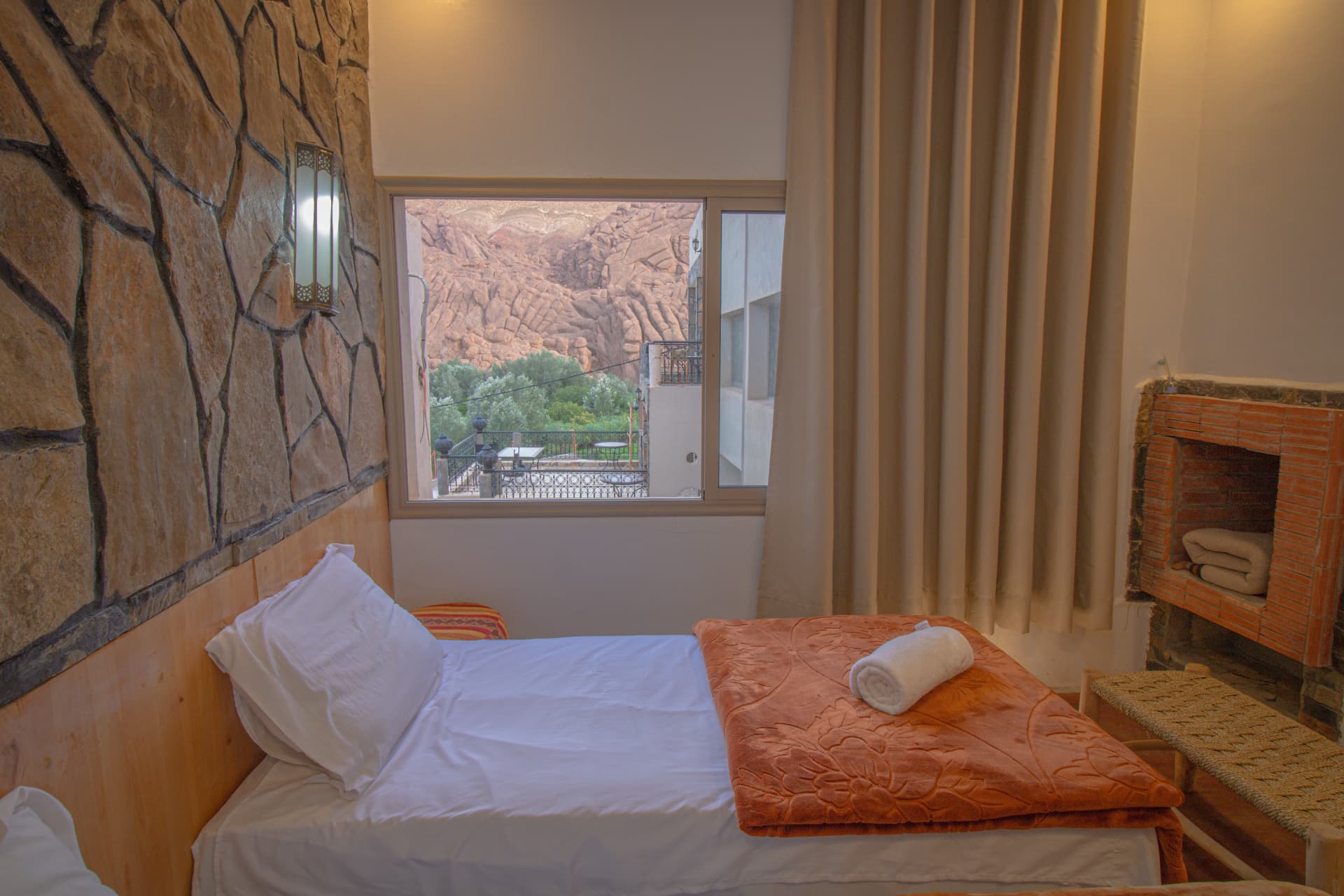 SAGHRO — bed with warm throw, brick fireplace and canyon window view