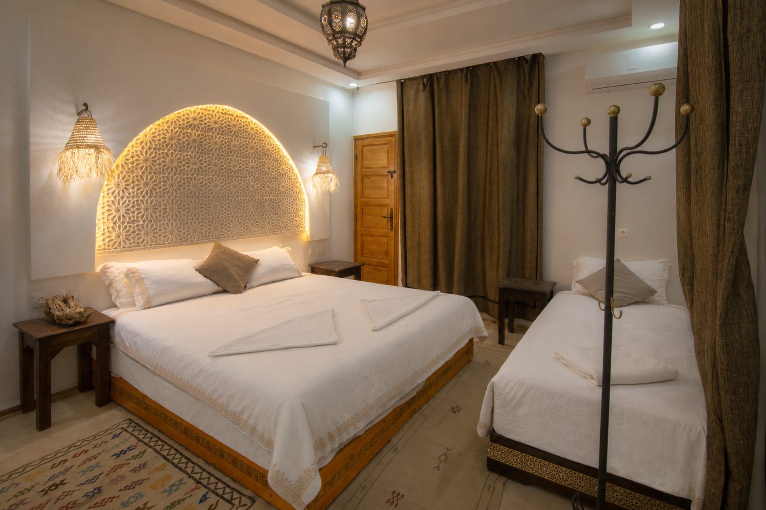 AMENTI — bedroom with lit carved arch and balcony curtains