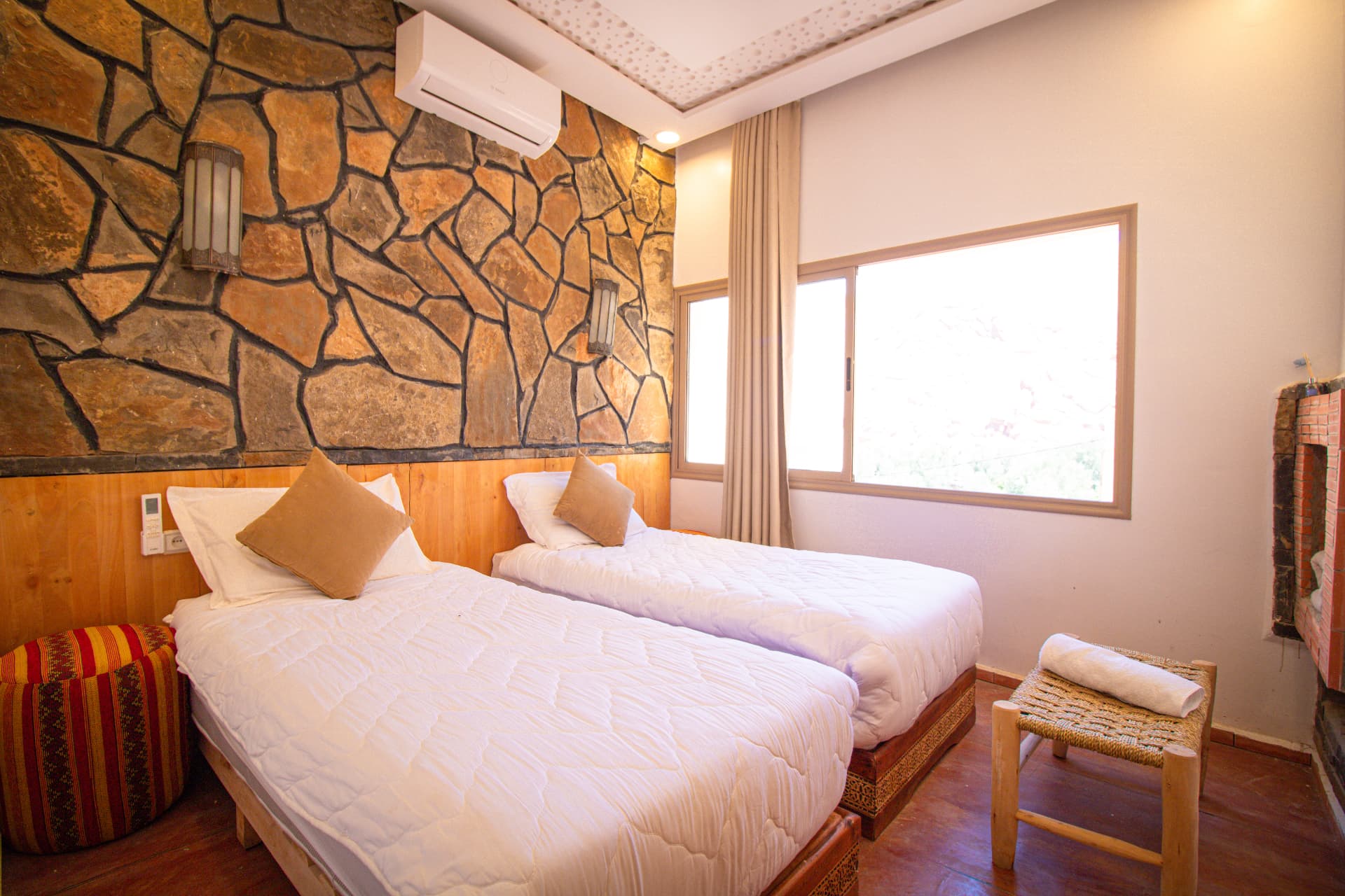 Twin room with stone feature wall and fireplace at Riad Canyon Dades in the Dades Gorges