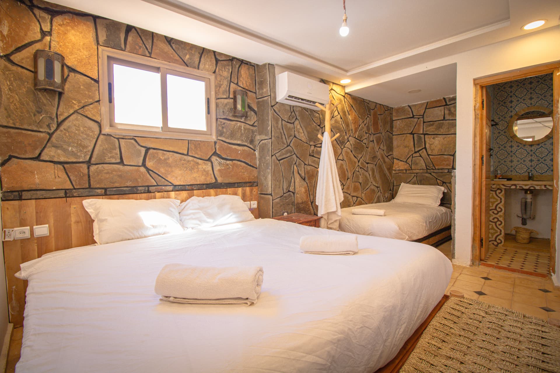 OUARZAZAT — wide room with dry-stone walls, double bed, extra single bed and tiled bathroom