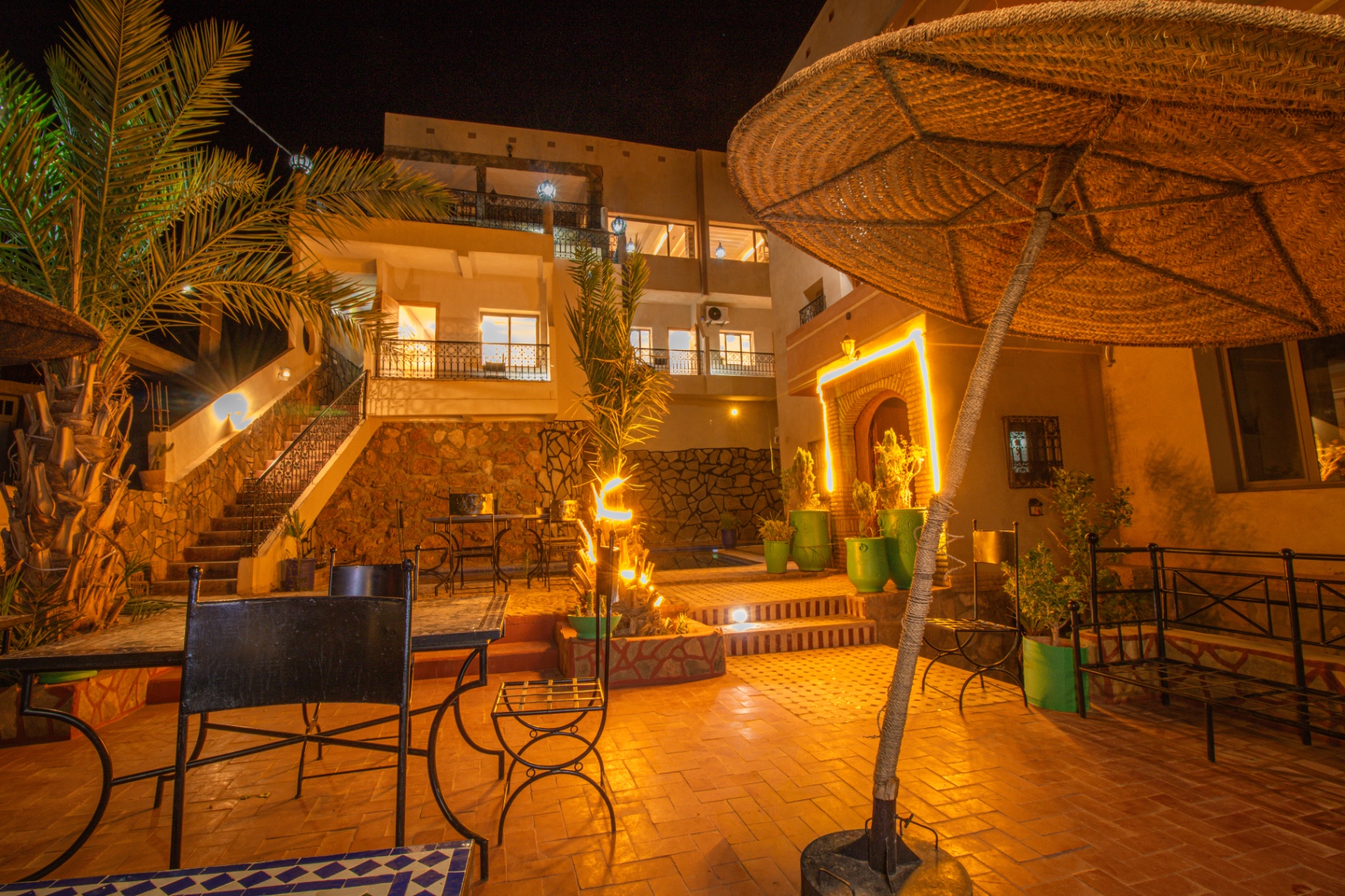 Terrace lounge of Riad Canyon Dades glowing under straw parasols at night, Dades Valley
