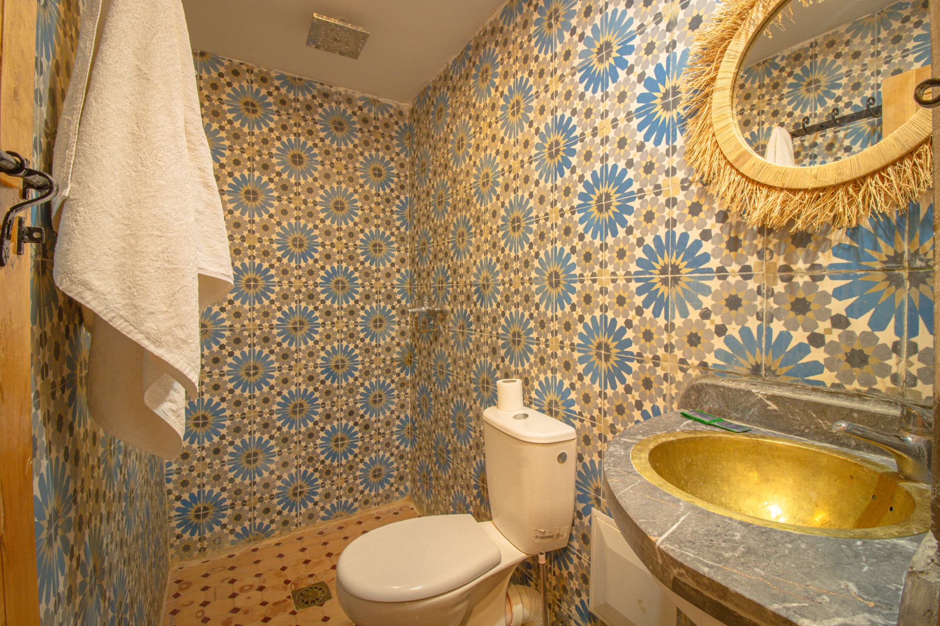 MARZOUGA — bathroom in blue and gold zellige with brass basin and raffia mirror