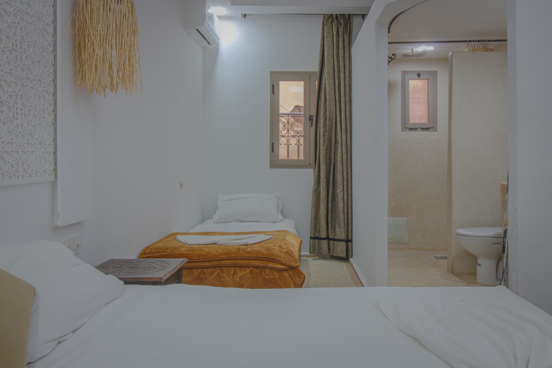 TALA — beds at dusk with soft lantern light and open bathroom beyond
