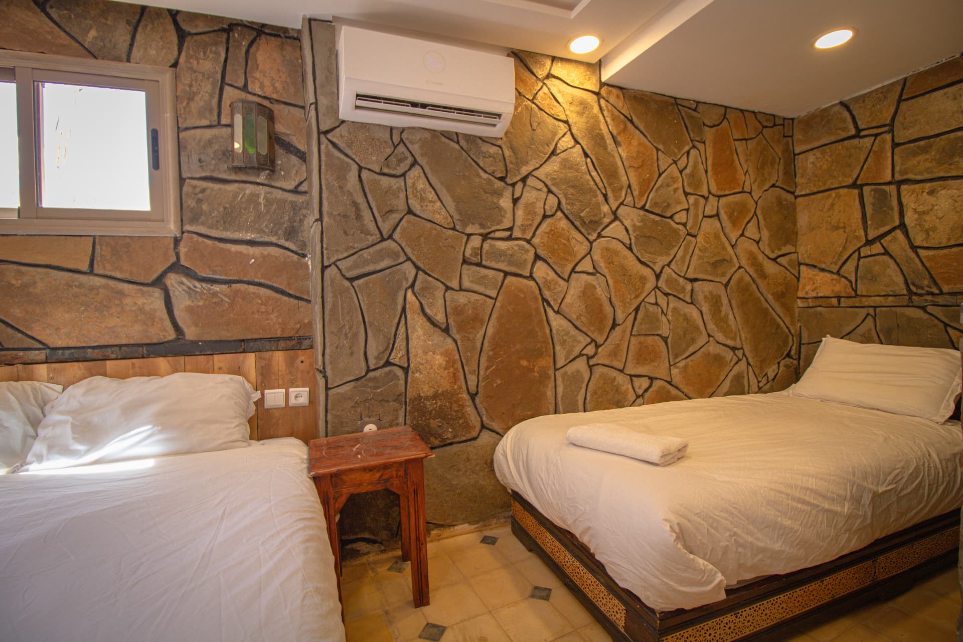 OUARZAZAT — beds against the warm stone wall with Moorish lantern