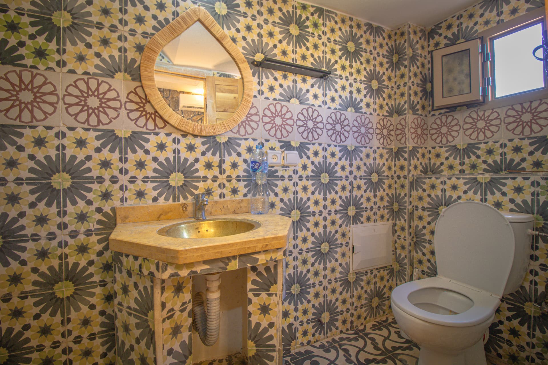 ZAGORA — bathroom vanity with patterned tiles and teardrop raffia mirror