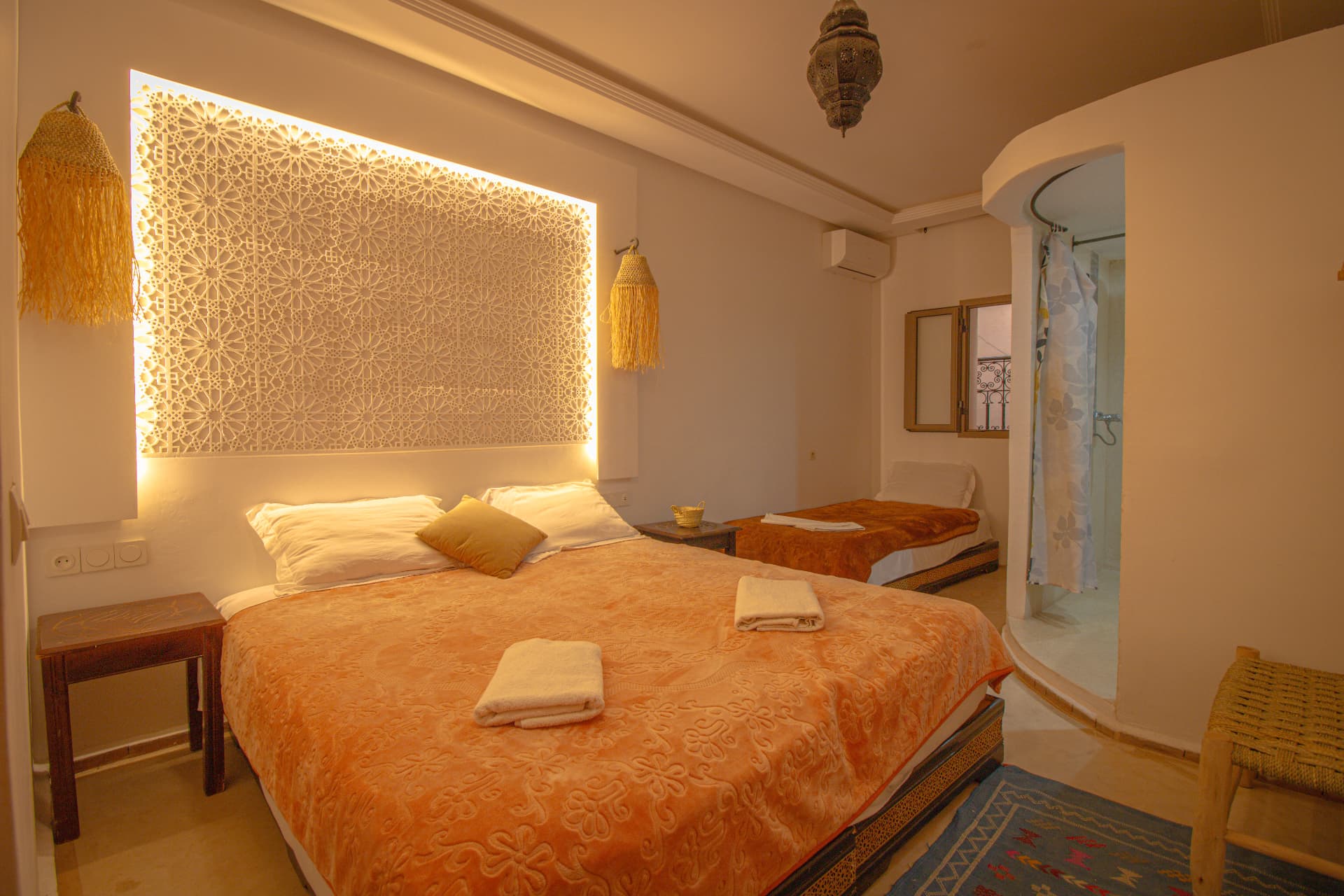 AFRI — wide bedroom with lit carved plaster headboard, double and single bed