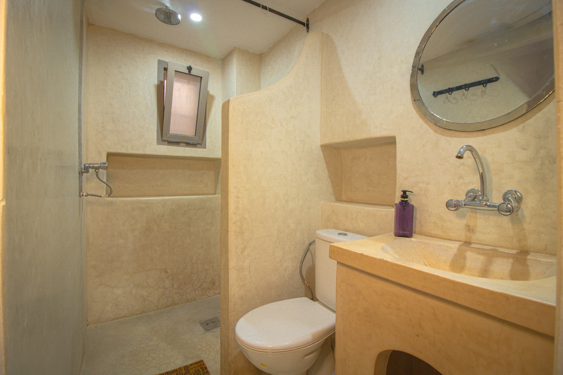 DADES — tadelakt bathroom with round mirror and walk-in rain shower