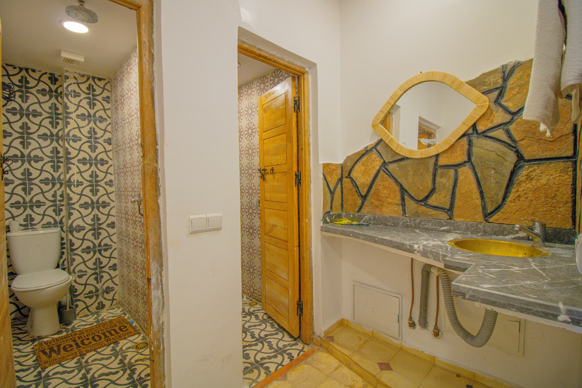 TAZDYI — bathroom with patterned tiles, marble vanity and brass basin