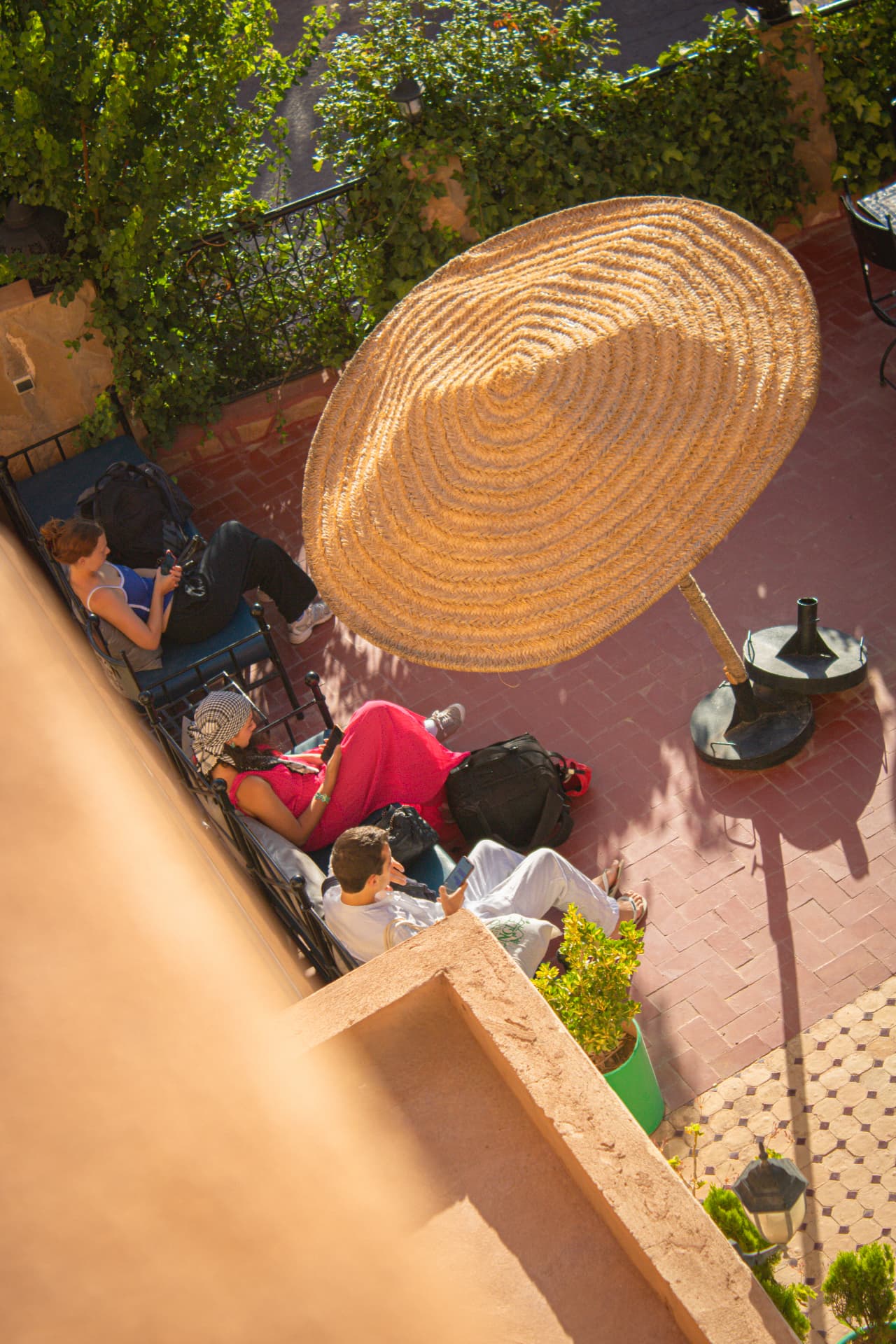 Guests relaxing under a straw parasol on the terrace of Riad Canyon Dades guesthouse