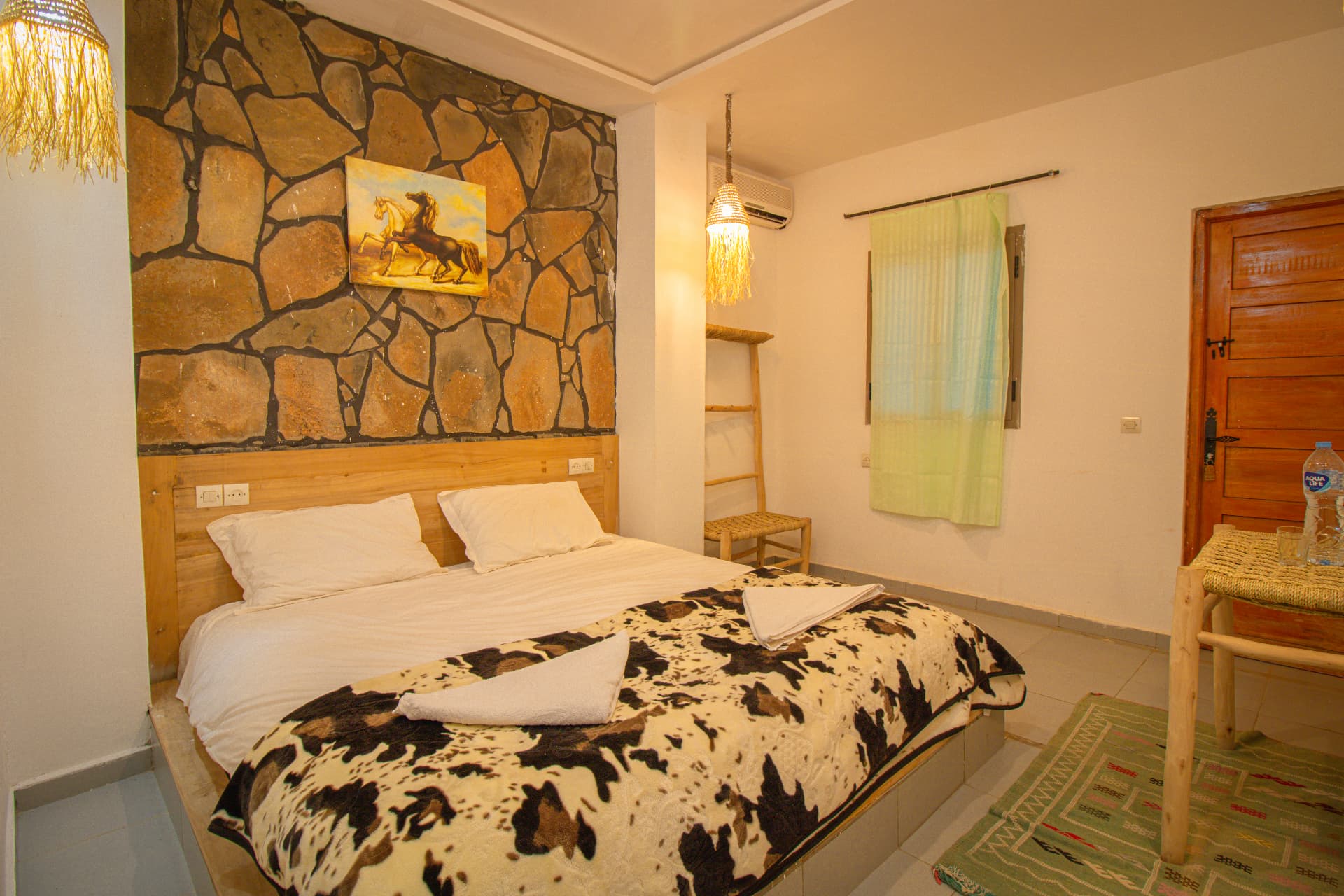 AYOUR — double bed beneath the stone wall with woven lanterns and Berber rug