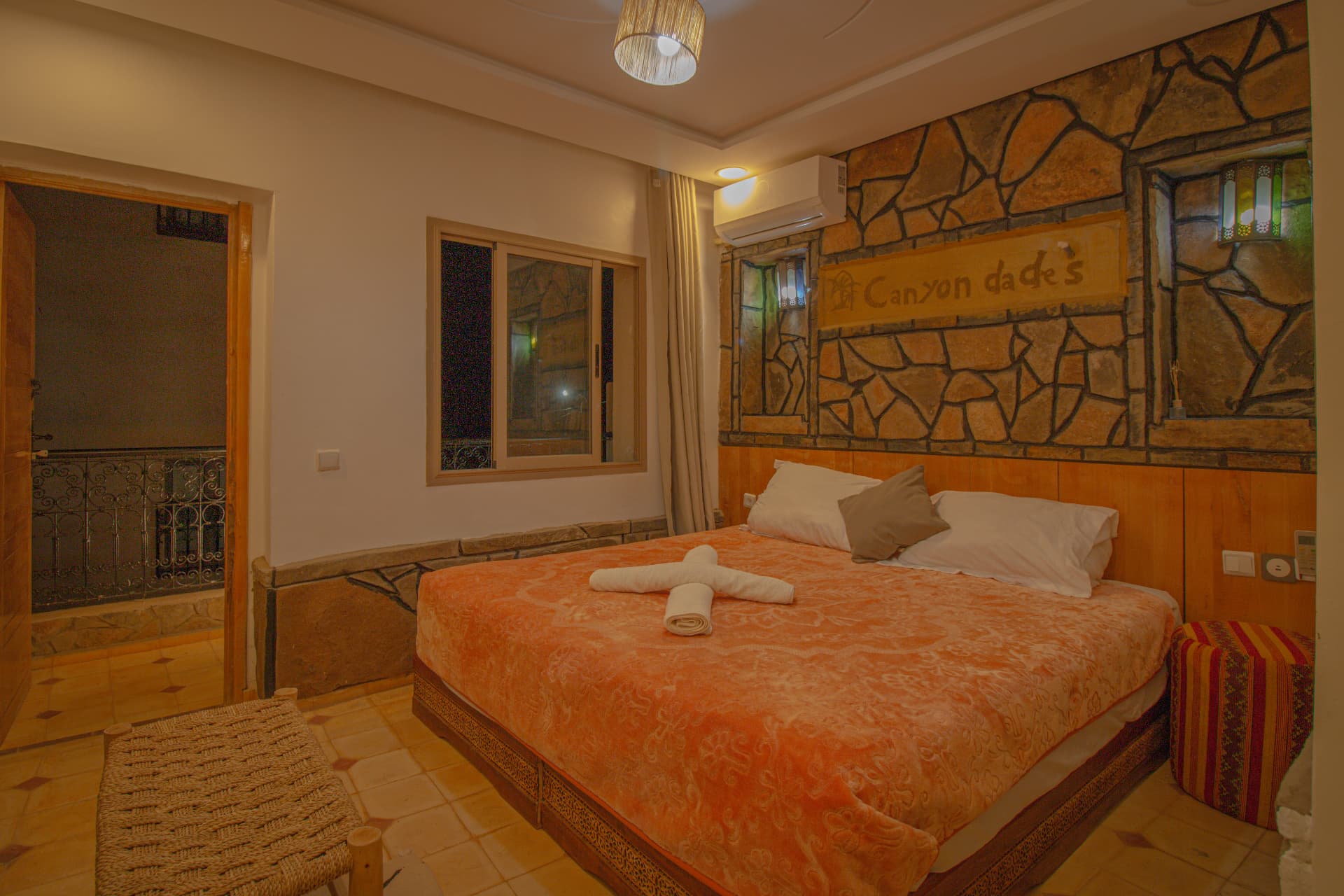 ZIZ — double bed beneath the carved Canyon Dades sign with stained-glass niches and balcony doorway