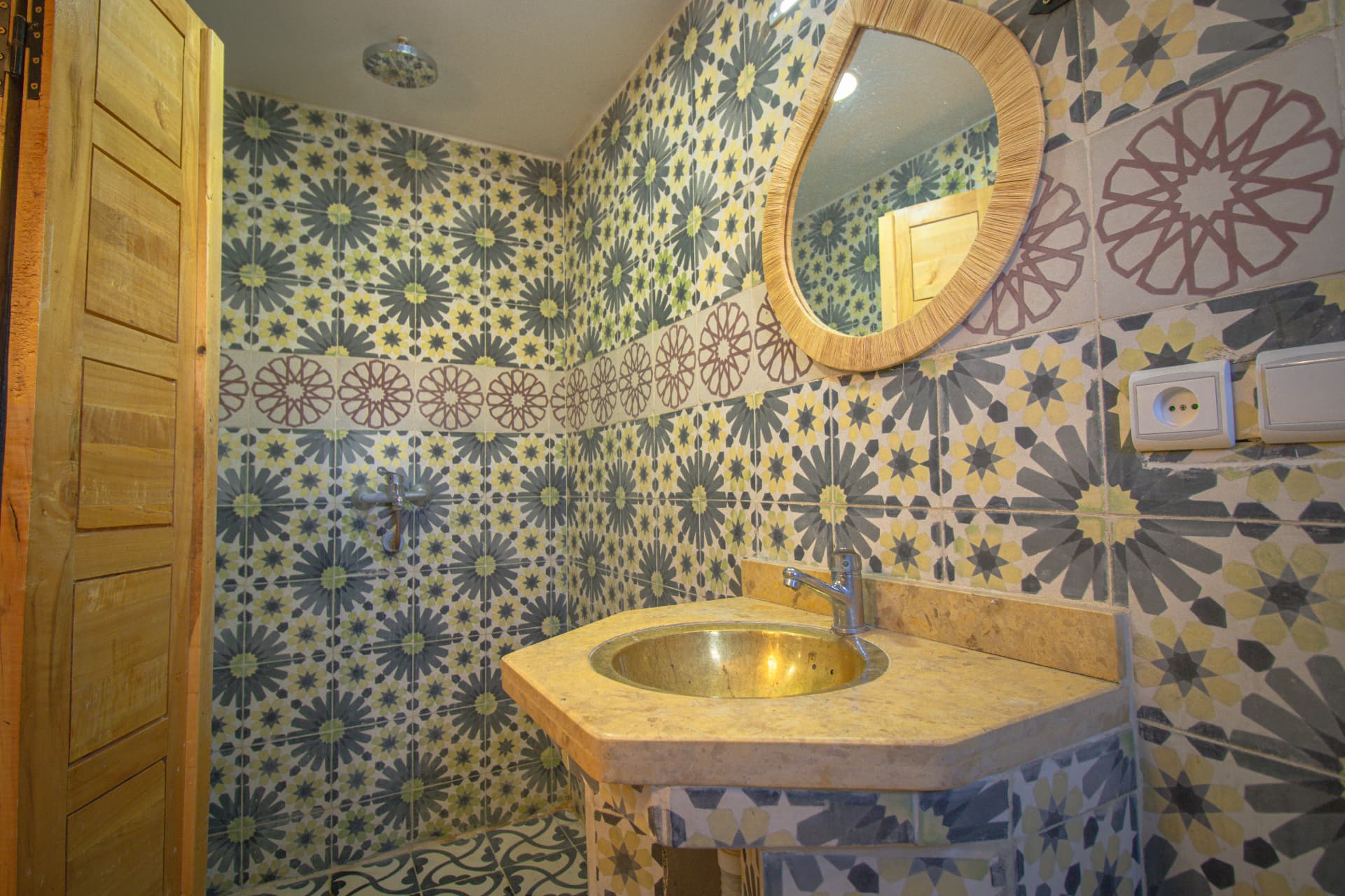 ZAGORA — bathroom in green zellige with brass basin and raffia mirror