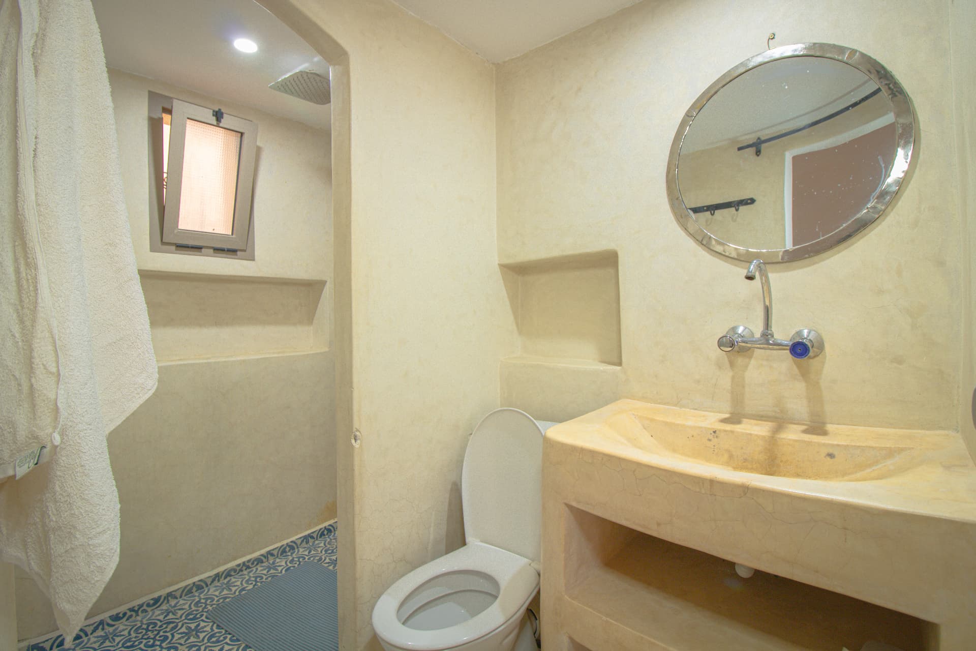 TALA — tadelakt bathroom with round mirror, carved basin and rain shower