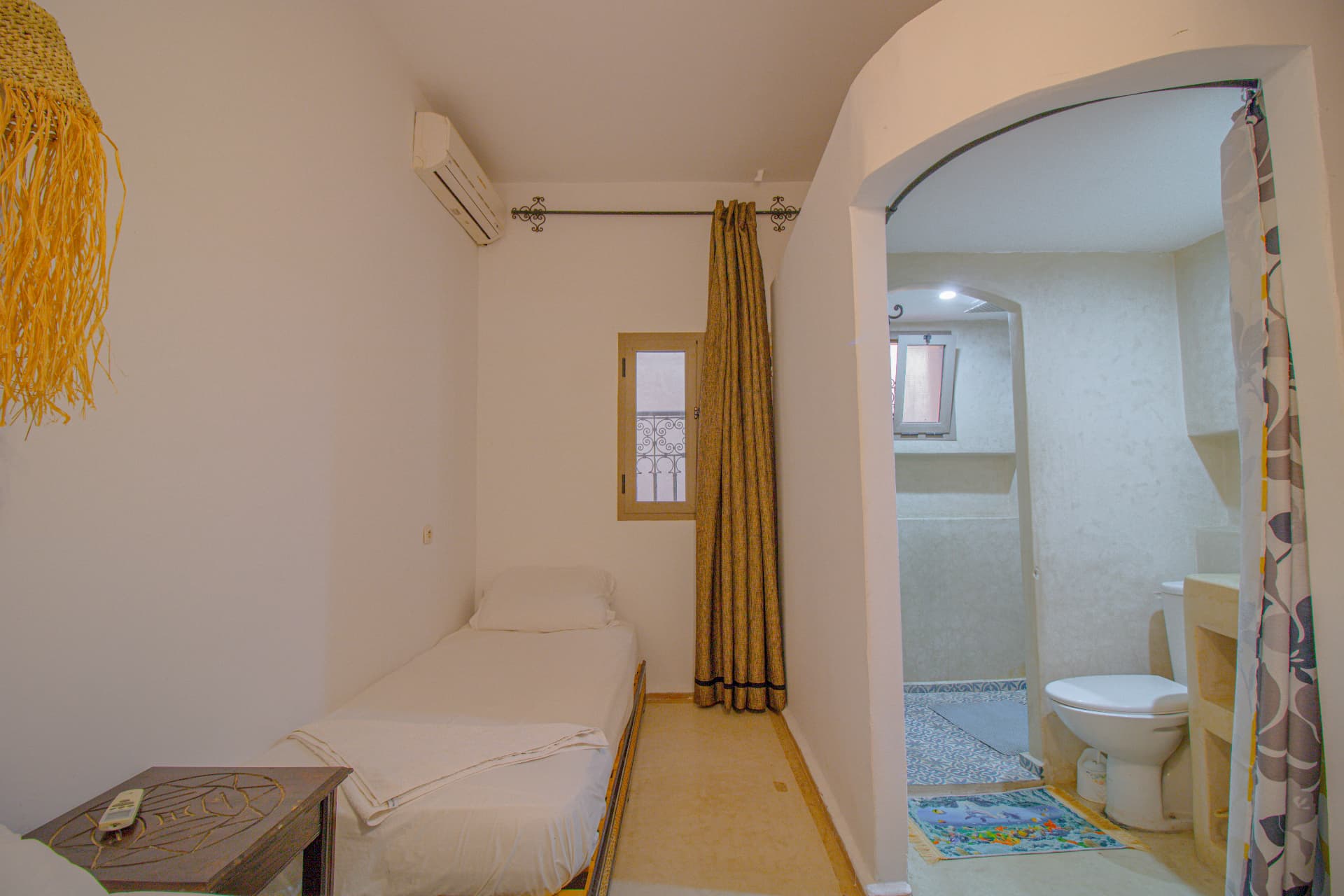 TALA — single bed, window with wrought-iron balcony and arched passage to the bathroom