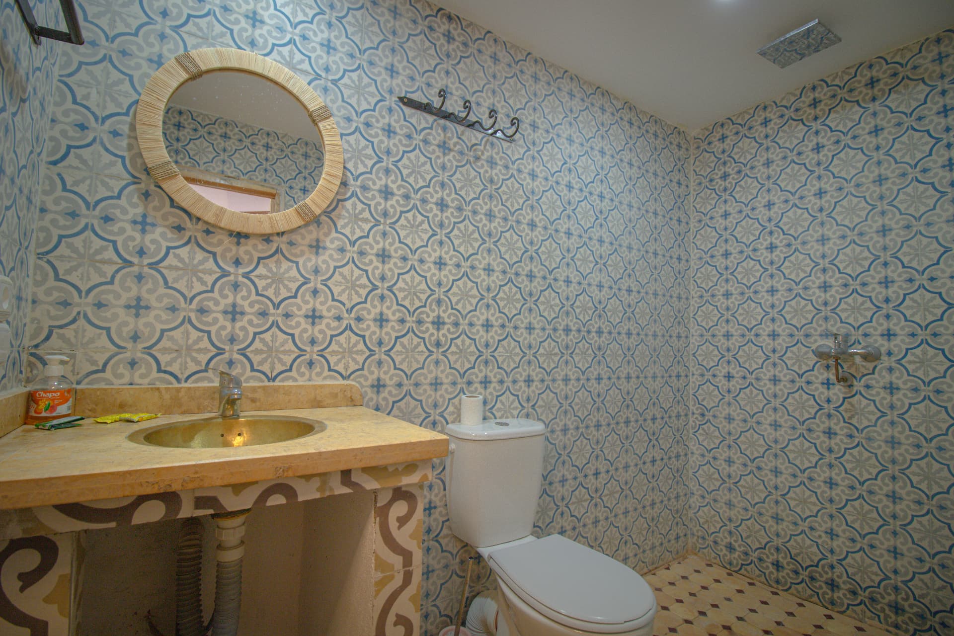 OUARZAZAT — bathroom in blue patterned zellige with brass basin and round mirror