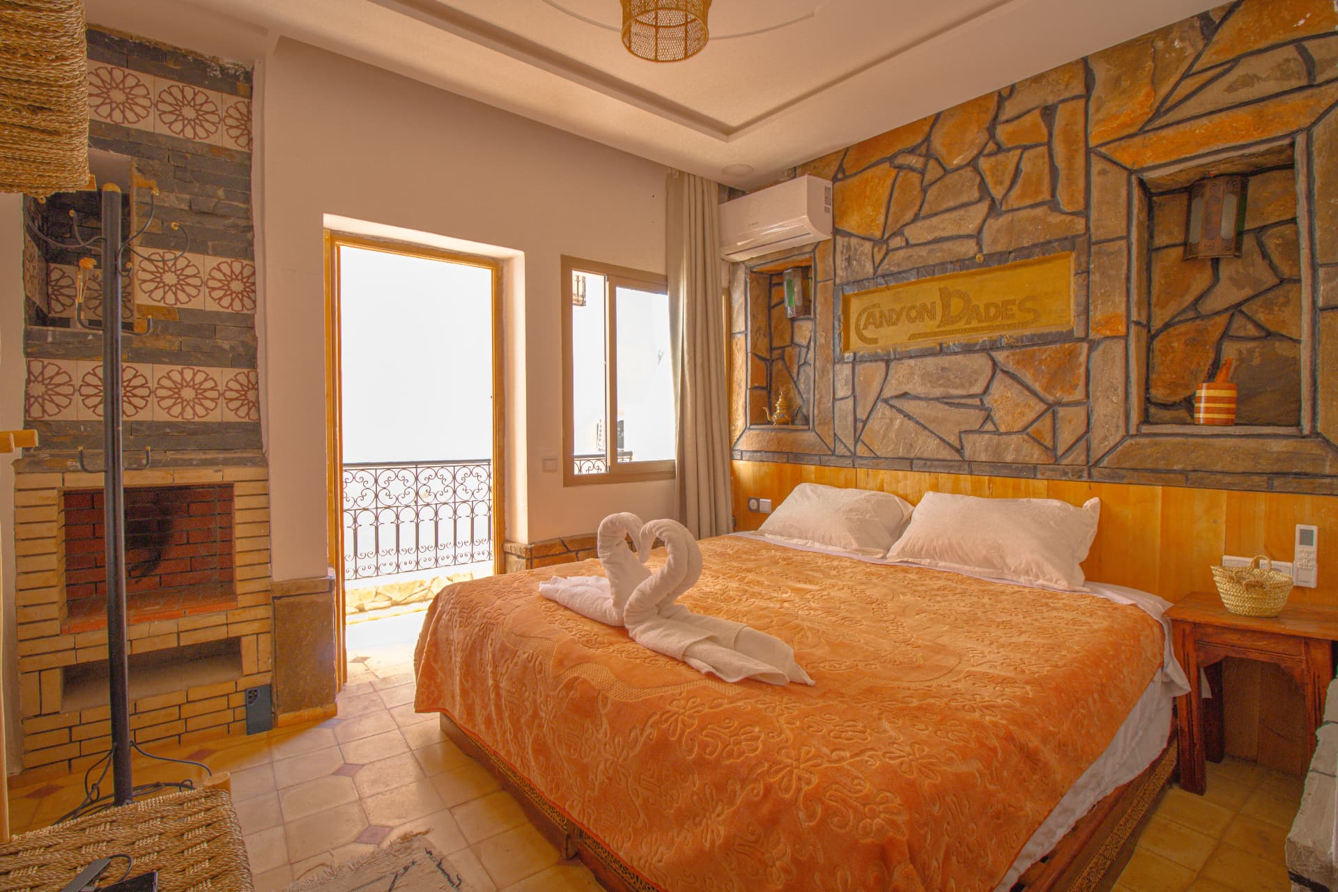 MARZOUGA — wide room view with stone feature wall, double bed, fireplace and doorway to the terrace