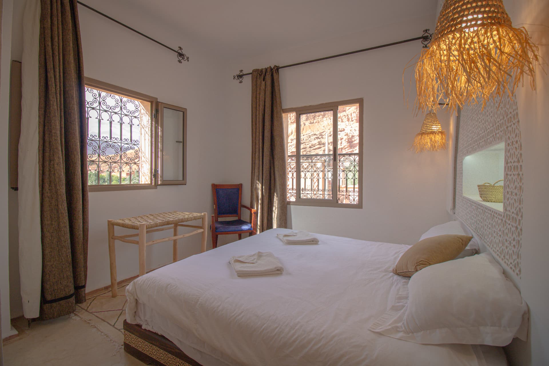 WARROU — wide bedroom with two windows onto the canyon and carved arch headboard