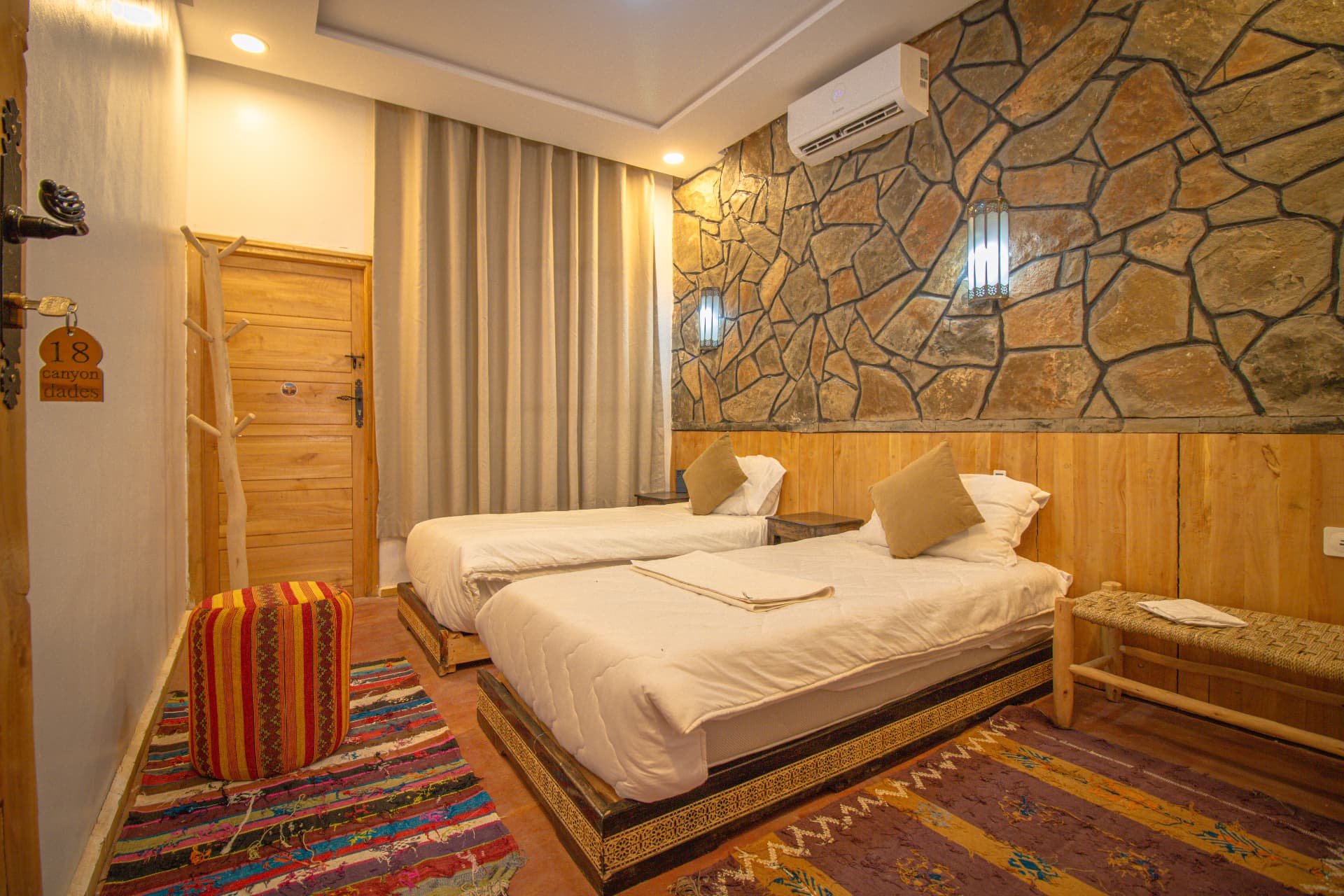 TODRA — wide twin room view with stone feature wall, lantern sconces and Berber rugs