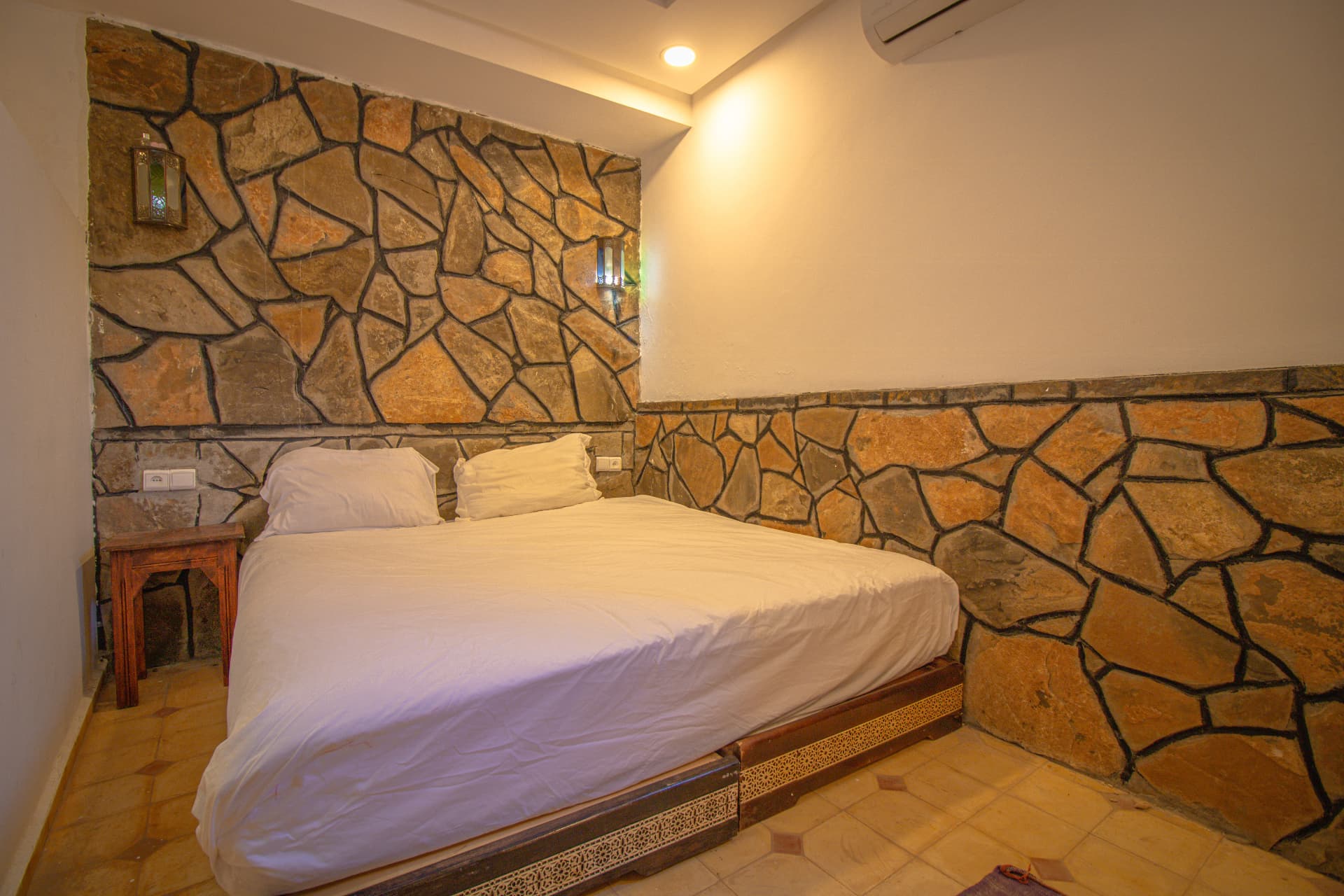 TAZDYI — double bed against the stone feature wall with lantern sconces