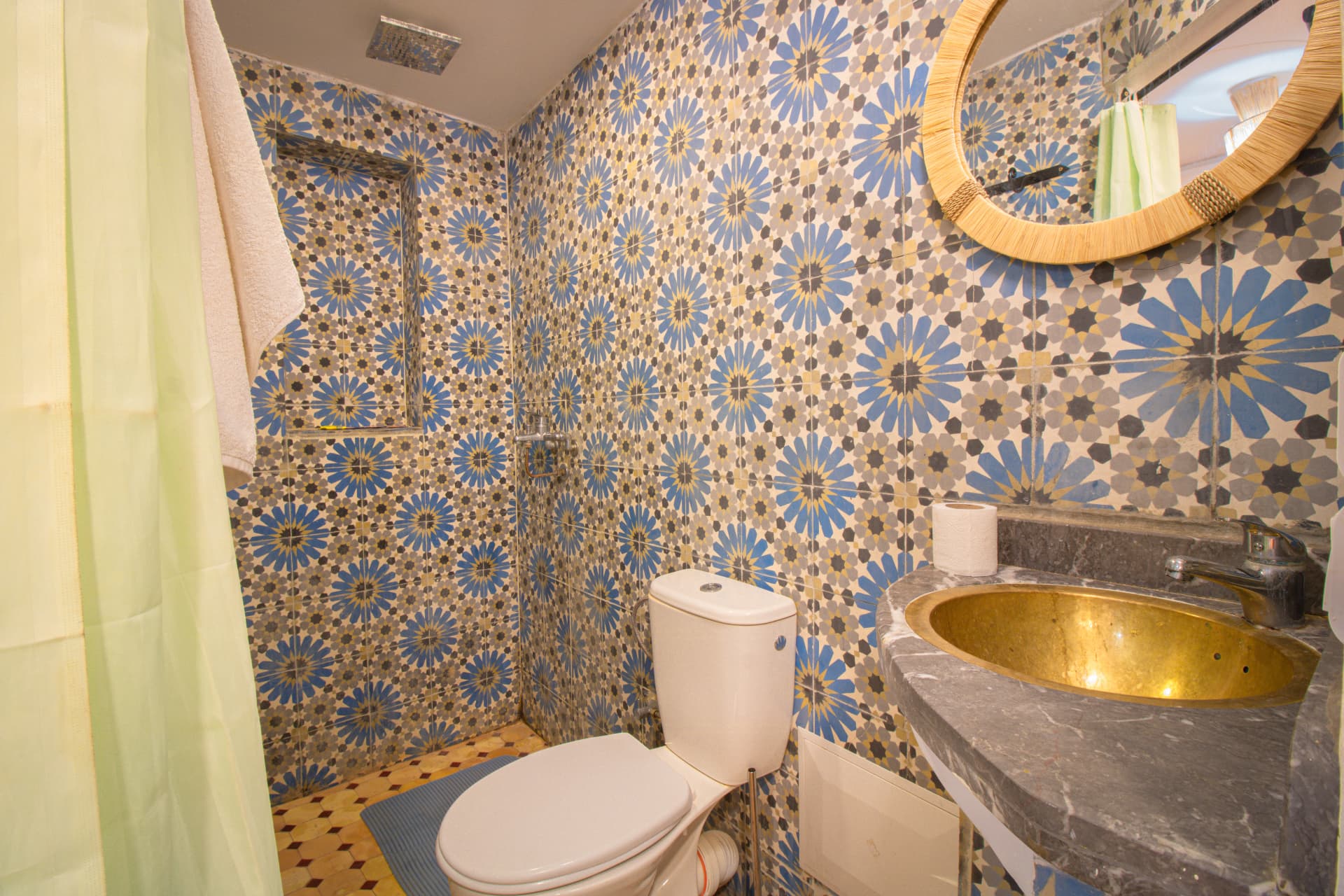 ZIZ — bathroom in blue floral zellige with brass basin and raffia mirror